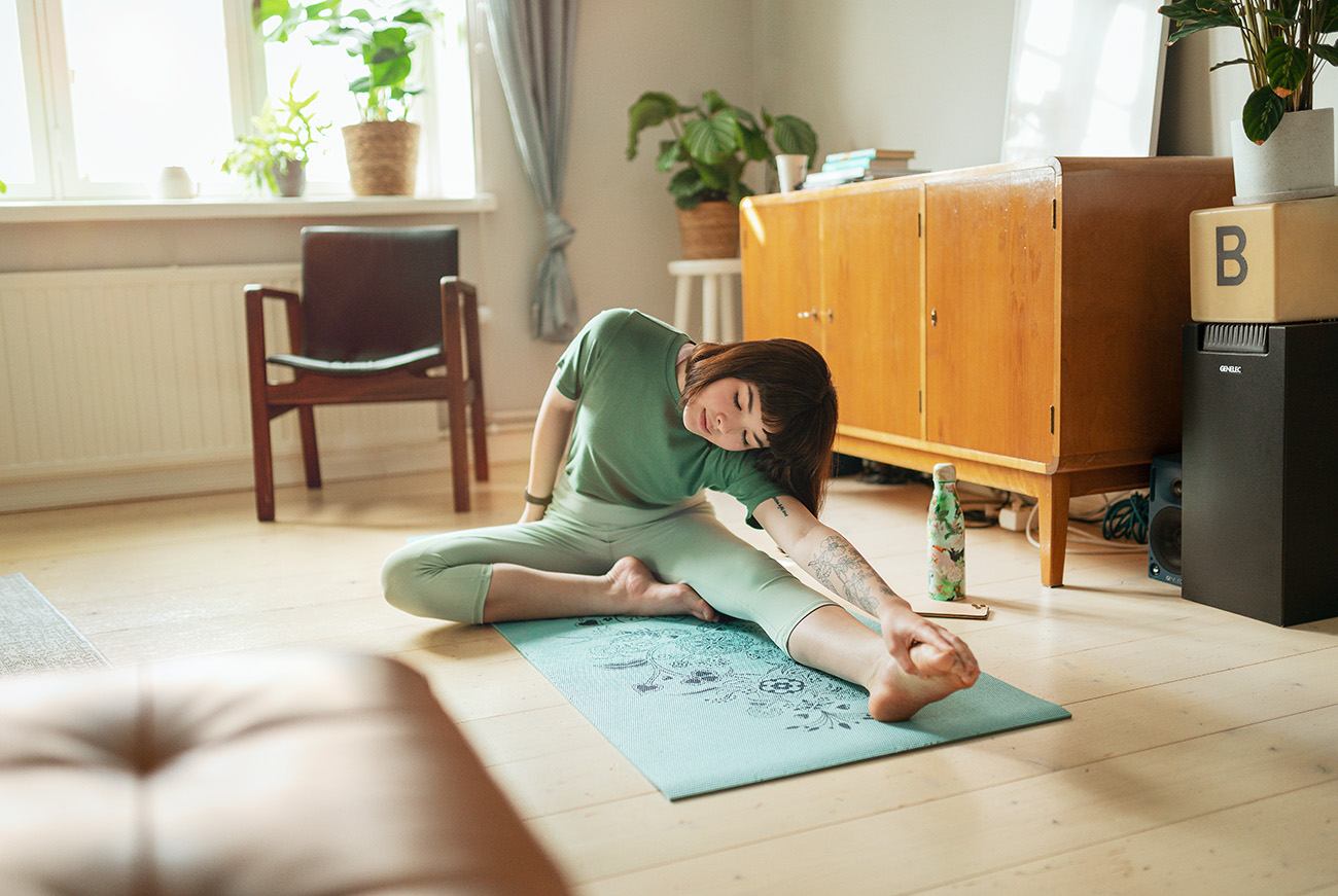 Komfort cieplny w mieszkaniu – kobieta ćwicząca jogę na macie rozłożonej na podłodze