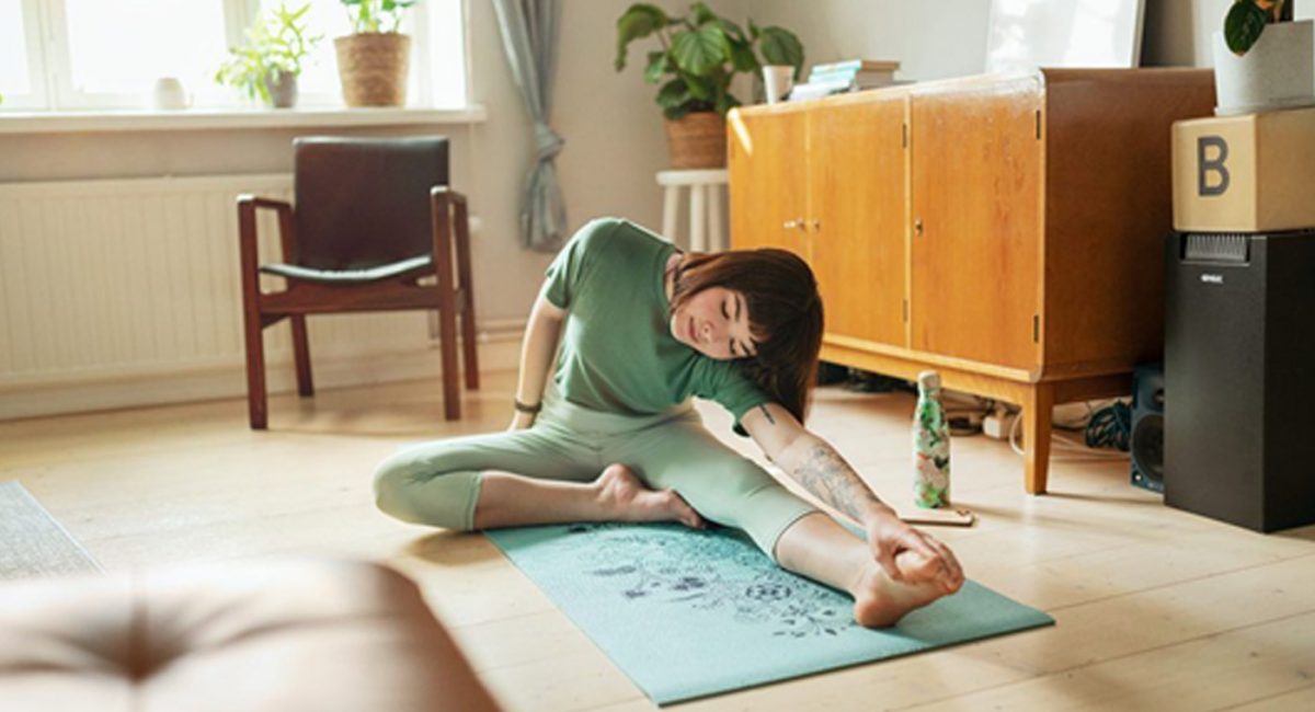 Komfort cieplny w mieszkaniu – kobieta ćwicząca jogę na macie rozłożonej na podłodze